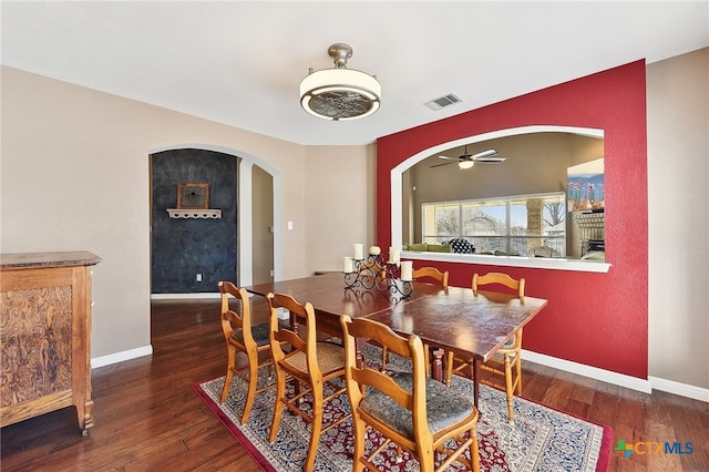 dining area featuring visible vents, arched walkways, baseboards, and wood finished floors