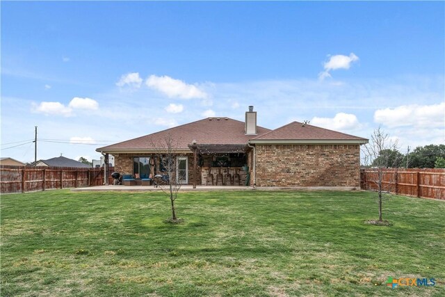 rear view of property featuring a patio, a fenced backyard, and a lawn