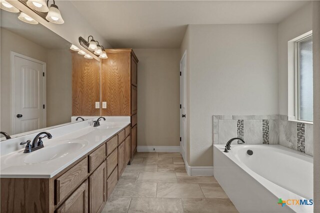 bathroom featuring plenty of natural light, a sink, and baseboards