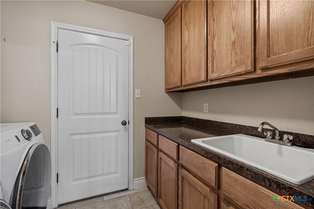 washroom with washer / clothes dryer, light tile patterned flooring, a sink, and cabinet space