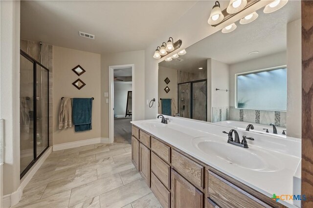 full bathroom with double vanity, visible vents, a stall shower, a sink, and baseboards