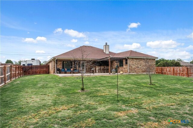 rear view of house featuring brick siding, a chimney, a fenced backyard, and a patio area