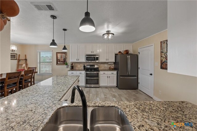 kitchen with stainless steel appliances, visible vents, white cabinetry, and a sink