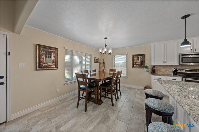 dining room featuring baseboards, a textured ceiling, and a notable chandelier