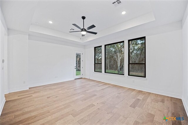 unfurnished room with a tray ceiling, light hardwood / wood-style flooring, and ceiling fan