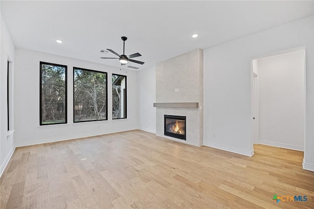 unfurnished living room with a tile fireplace, light hardwood / wood-style floors, and ceiling fan