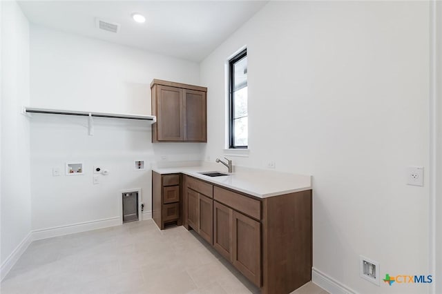 laundry room featuring gas dryer hookup, sink, cabinets, washer hookup, and electric dryer hookup