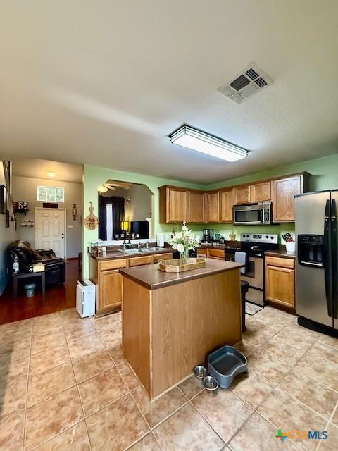 kitchen featuring light tile patterned floors, a center island, and appliances with stainless steel finishes