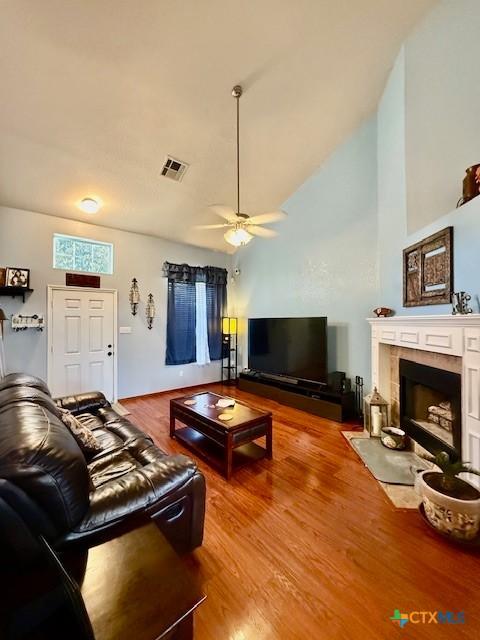 living room featuring hardwood / wood-style floors, a fireplace, high vaulted ceiling, and ceiling fan