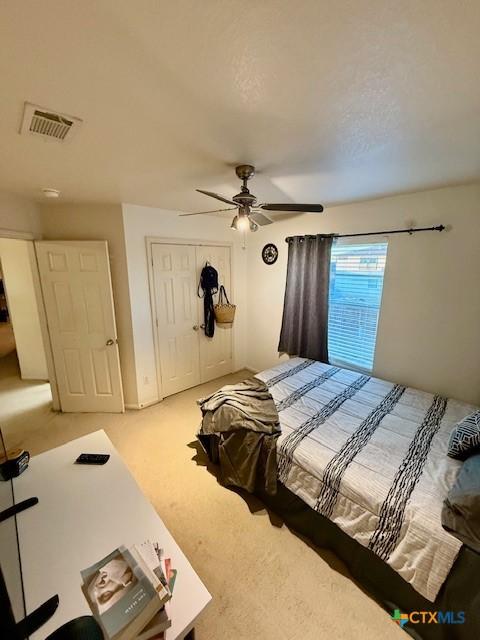 carpeted bedroom featuring ceiling fan and a closet