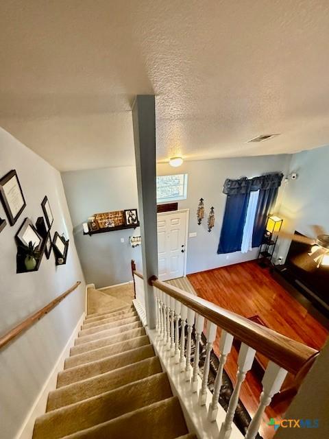 stairs featuring a textured ceiling