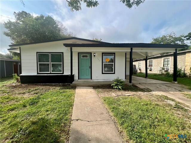 view of front of property with a carport and a front lawn