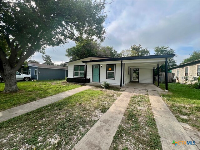 ranch-style home featuring a carport and a front lawn