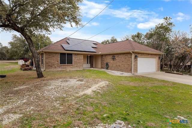 view of front of property featuring a garage, a front yard, and solar panels