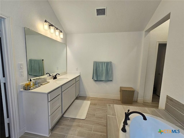 2961 Grove Way, Seguin, TX 78155 - bathroom featuring lofted ceiling, vanity, a garden tub, and wood finish floors