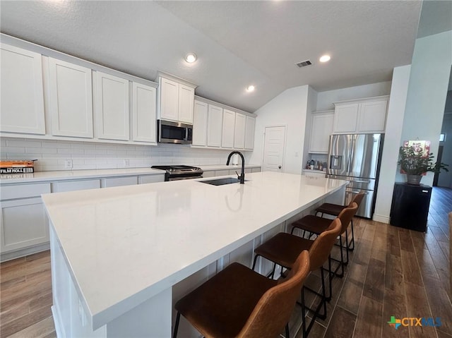 2961 Grove Way, Seguin, TX 78155 - kitchen featuring stainless steel appliances, decorative backsplash, dark wood-style flooring, vaulted ceiling, and an island with sink