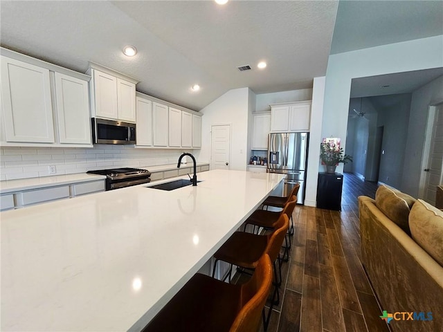 2961 Grove Way, Seguin, TX 78155 - kitchen featuring stainless steel appliances, a kitchen bar, dark wood finished floors, decorative backsplash, and light countertops