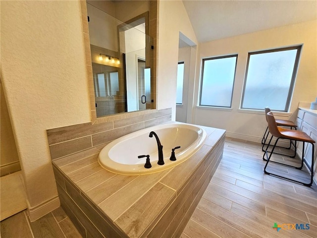 2961 Grove Way, Seguin, TX 78155 - full bathroom with a garden tub, tiled shower, wood finished floors, lofted ceiling, and a textured wall