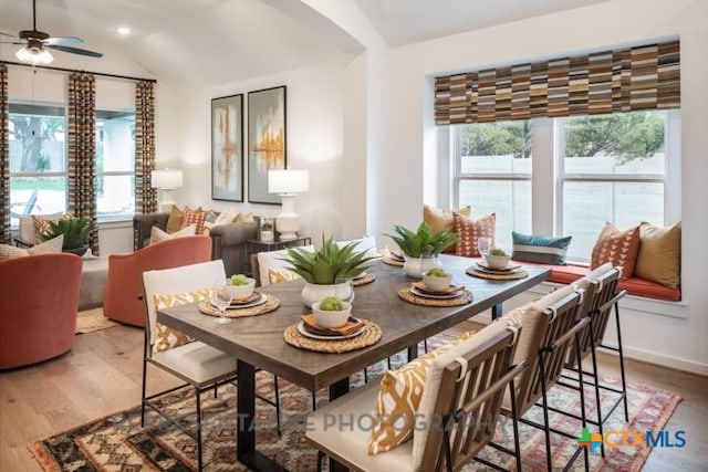 dining space with light wood-style floors, arched walkways, ceiling fan, and vaulted ceiling