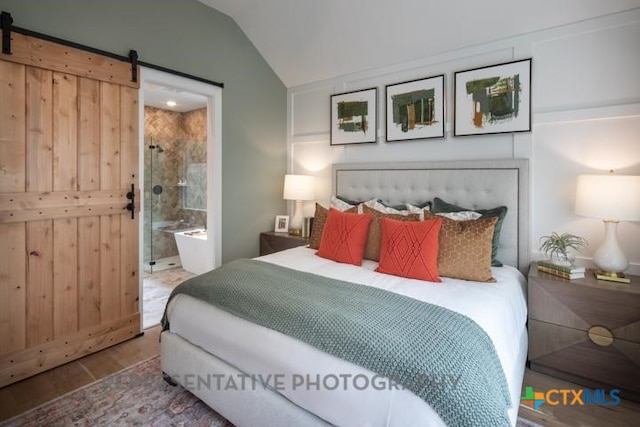 bedroom with a barn door, wood finished floors, and lofted ceiling