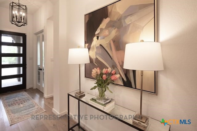 foyer entrance with baseboards, a chandelier, and wood finished floors