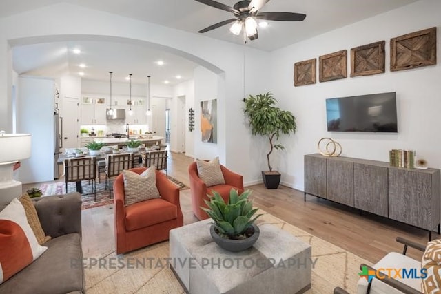 living area with recessed lighting, arched walkways, a ceiling fan, and light wood-type flooring