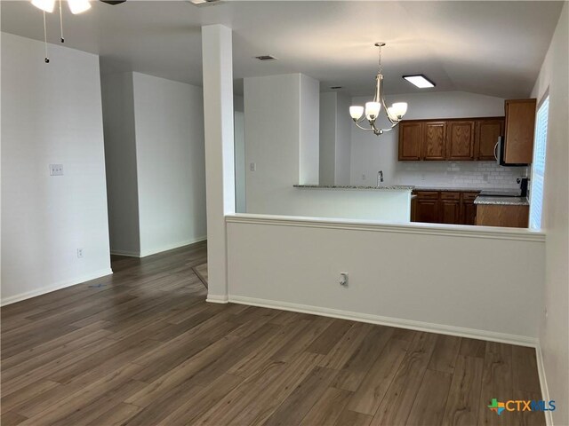 512 Constellation Dr, Killeen, TX 76542 - kitchen featuring dark wood finished floors, vaulted ceiling, a chandelier, decorative backsplash, and brown cabinets