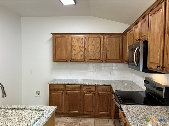 512 Constellation Dr, Killeen, TX 76542 - kitchen with electric stove, stainless steel microwave, vaulted ceiling, decorative backsplash, and light stone counters