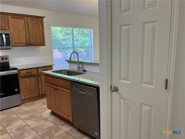 512 Constellation Dr, Killeen, TX 76542 - kitchen with stainless steel appliances, backsplash, light stone counters, and brown cabinets