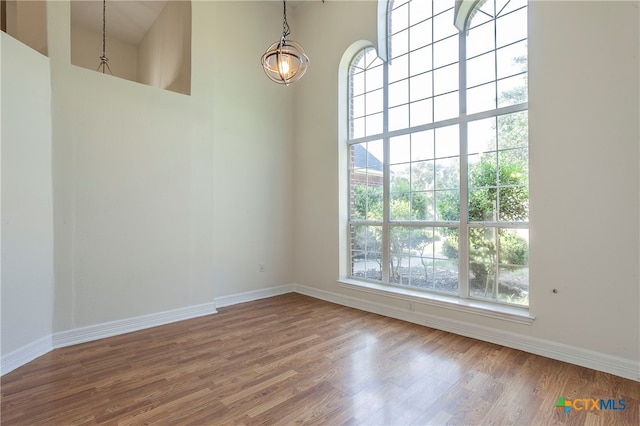 empty room featuring a towering ceiling and hardwood / wood-style flooring