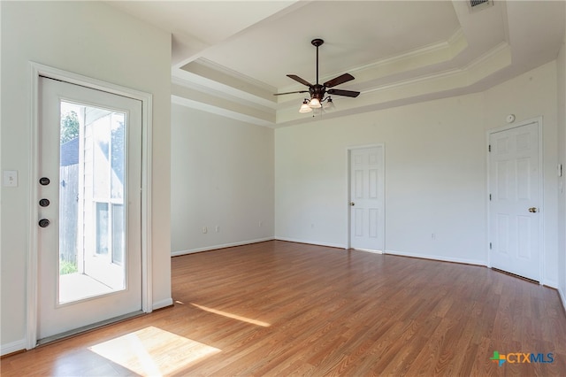 interior space with a tray ceiling, hardwood / wood-style floors, ceiling fan, and crown molding