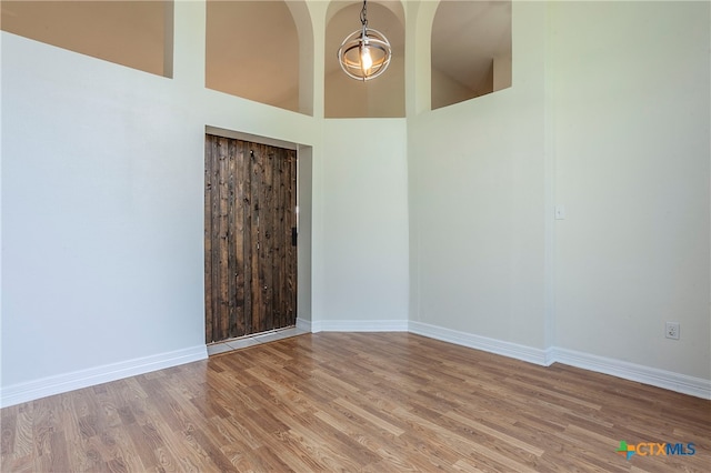 spare room featuring wood-type flooring and a towering ceiling