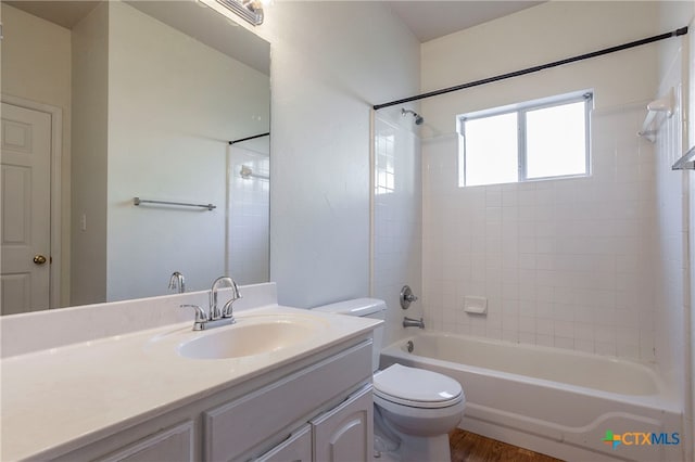 full bathroom with hardwood / wood-style flooring, vanity, toilet, and tiled shower / bath