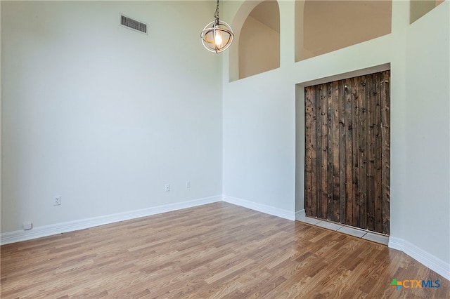 unfurnished room with a high ceiling and light hardwood / wood-style flooring