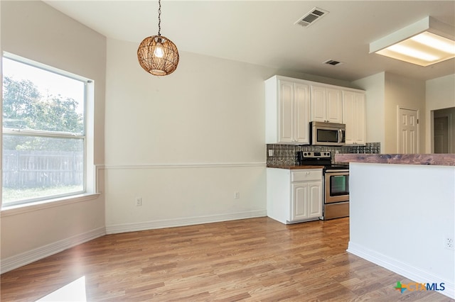 kitchen with a wealth of natural light, white cabinetry, light hardwood / wood-style flooring, and appliances with stainless steel finishes