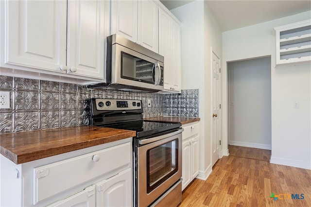 kitchen with wooden counters, stainless steel appliances, white cabinets, tasteful backsplash, and light hardwood / wood-style flooring