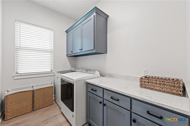 clothes washing area featuring light wood finished floors, independent washer and dryer, and cabinet space