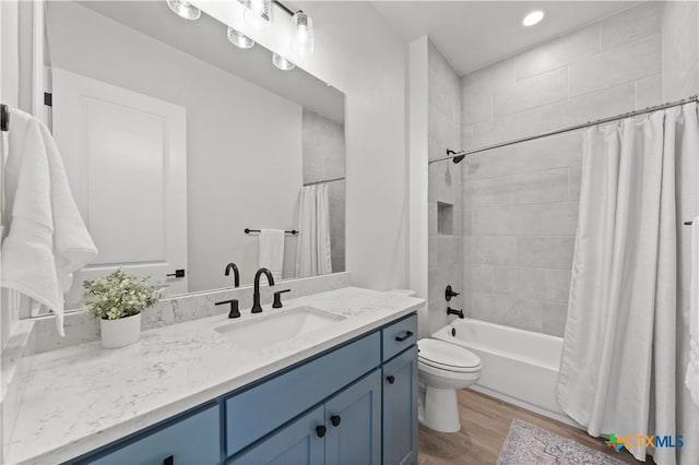 bathroom featuring recessed lighting, wood finished floors, shower / bath combo with shower curtain, toilet, and vanity