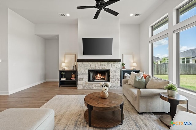 living room with ceiling fan, a wealth of natural light, visible vents, and wood finished floors