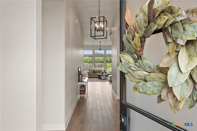 hallway featuring a notable chandelier, dark wood-style flooring, and baseboards