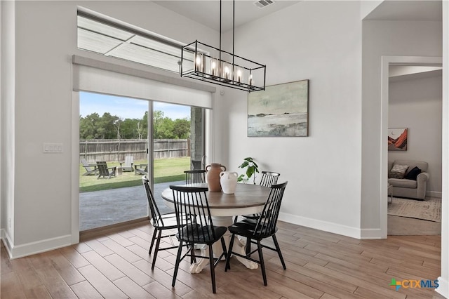 dining room featuring visible vents, a chandelier, wood finished floors, and baseboards