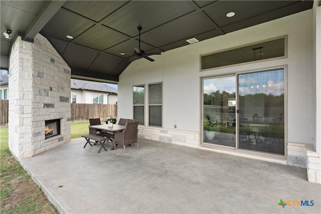 view of patio / terrace featuring visible vents, fence, ceiling fan, outdoor dining space, and an outdoor stone fireplace