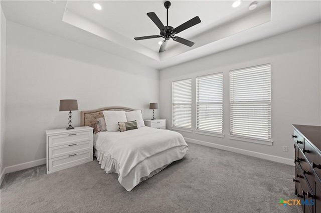 carpeted bedroom with a raised ceiling, ceiling fan, recessed lighting, and baseboards