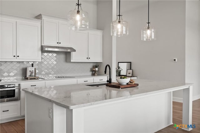 kitchen featuring a sink, under cabinet range hood, black electric cooktop, stainless steel oven, and backsplash