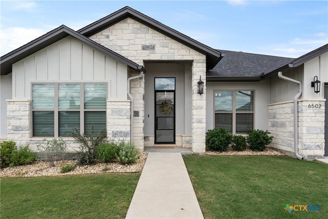 doorway to property featuring a lawn, board and batten siding, a shingled roof, and stone siding