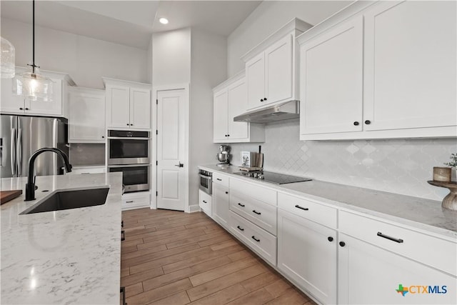 kitchen featuring white cabinetry, stainless steel appliances, under cabinet range hood, and a sink