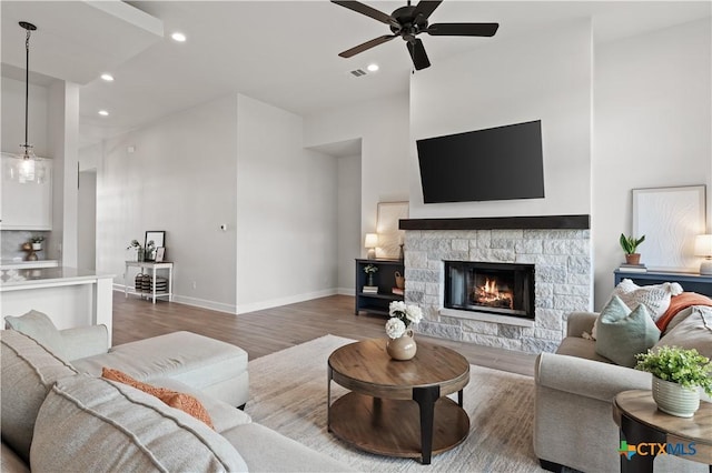 living area with recessed lighting, a fireplace, ceiling fan, baseboards, and wood finished floors