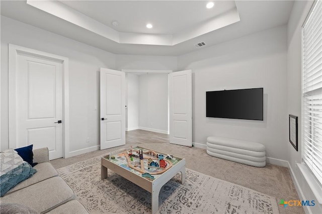 carpeted living room featuring baseboards, visible vents, a healthy amount of sunlight, and a tray ceiling