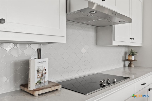 kitchen with light stone countertops, black electric stovetop, under cabinet range hood, white cabinets, and backsplash