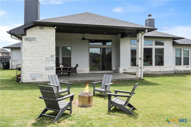 rear view of property with a ceiling fan, stone siding, a fire pit, and a chimney
